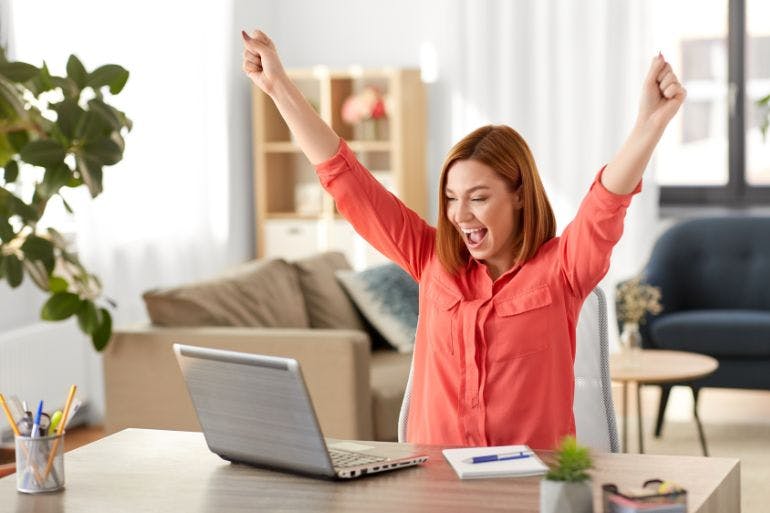 HR Software Benefits Female business owner excited seeing the benfits of HR software on laptop